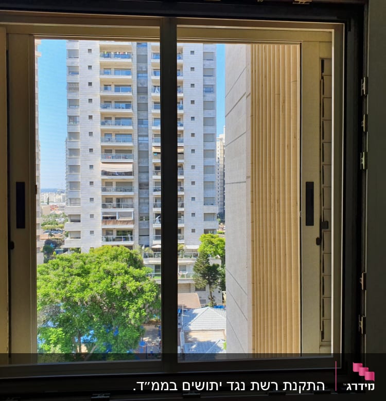 חלון אלומיניום עם מסגרת כהה ונוף עירוני